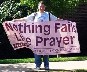Justin Vacula protests using a colorful FFRF banner
